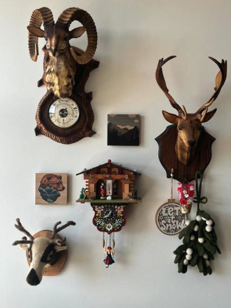 Wall of alpine curios including a cuckoo clock, carved deer and a ram's head barometer